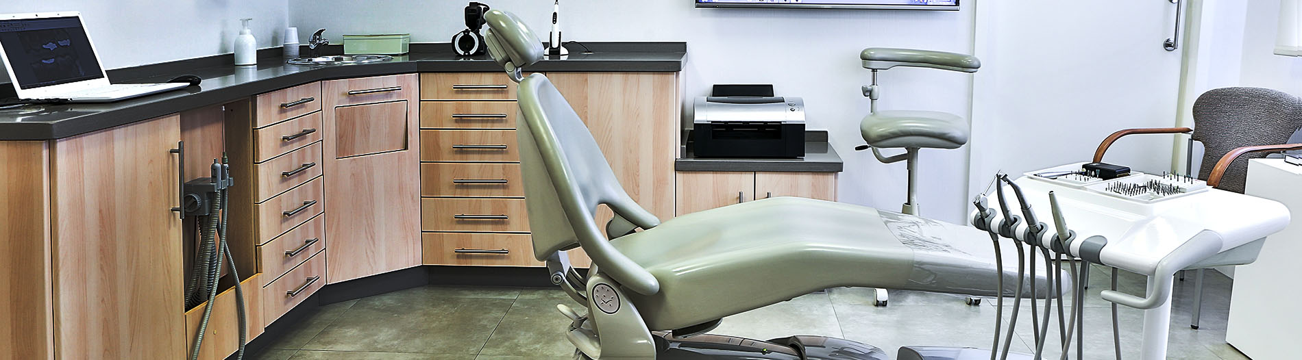 The image shows a modern dental clinic interior with various pieces of equipment, including a dental chair and an X-ray machine.