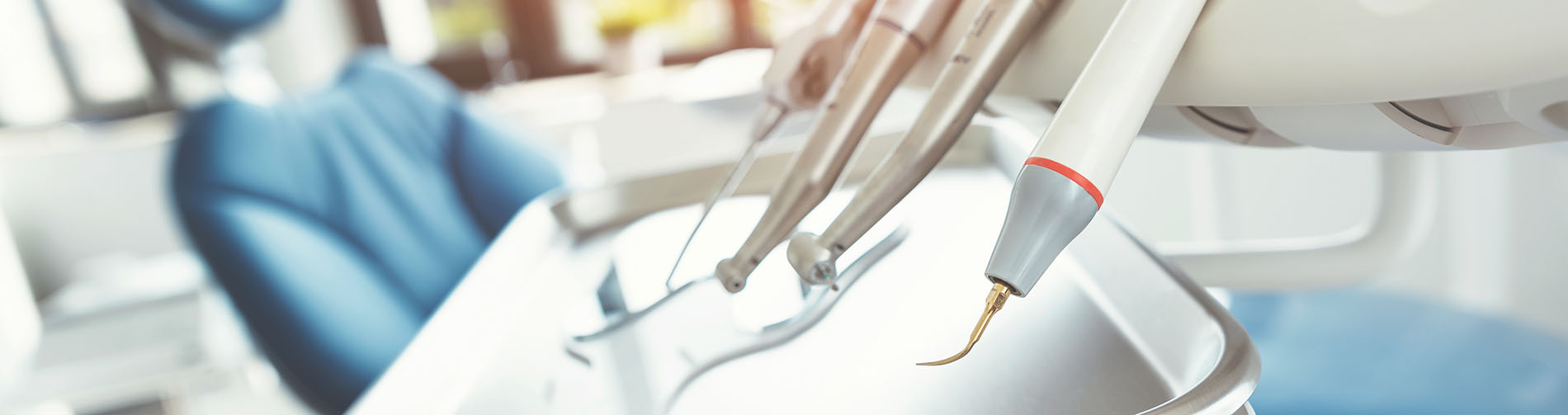 A person is seated in a dental chair, receiving care from a dental professional who stands behind them.